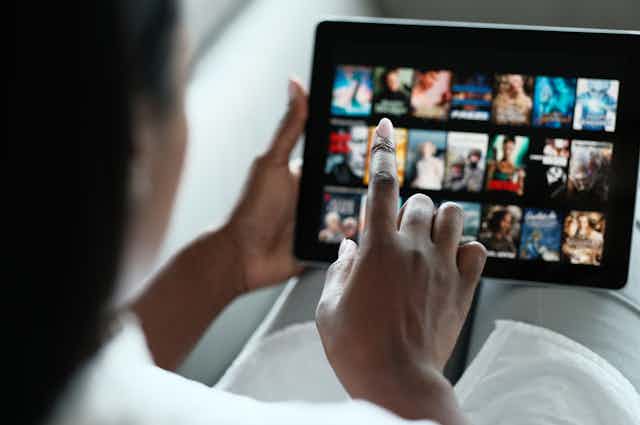 A person swiping through a video streaming service selection screen on a tablet