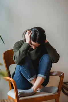 A young girl sits in a chair with her head in her hands.