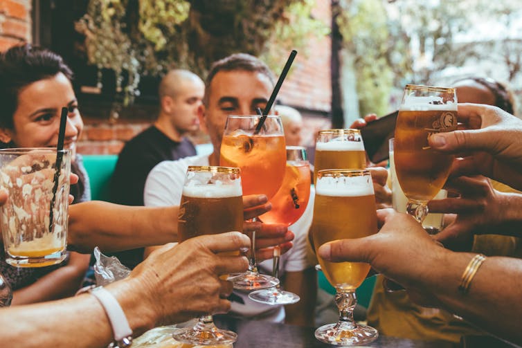 group of friends do cheers with drinks in pub
