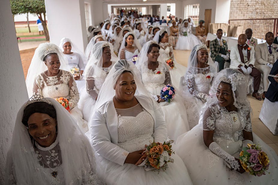 Seated brides in wedding dresses carrying bouquets of flowers.