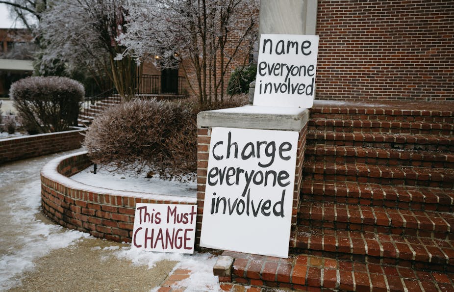 Three hand-written signs calling for action rest on a brick stair structure.