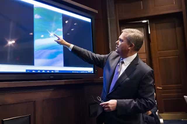 Wakil Direktur Intelijen Angkatan Laut Scott Bray memutar video tentang 'fenomena udara tak dikenal,' dan menunjuk ke sebuah titik di layar. 