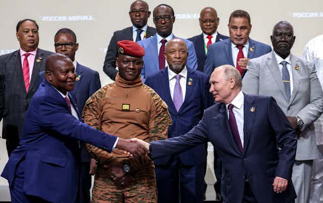 Vladimir Putin shakes hands with Mozambique President Filipe Nyusi surrounded by other African leaders at the 2023 Russia-Africa summit in St Petersburg, July 2023.