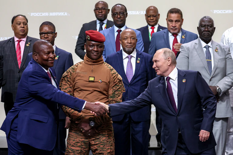 Vladimir Putin shakes hands with Mozambique President Filipe Nyusi surrounded by other African leaders at the 2023 Russia-Africa summit in St Petersburg, July 2023.
