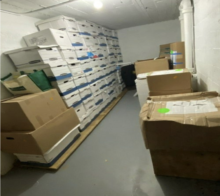 Boxes are stacked in a windowless room.