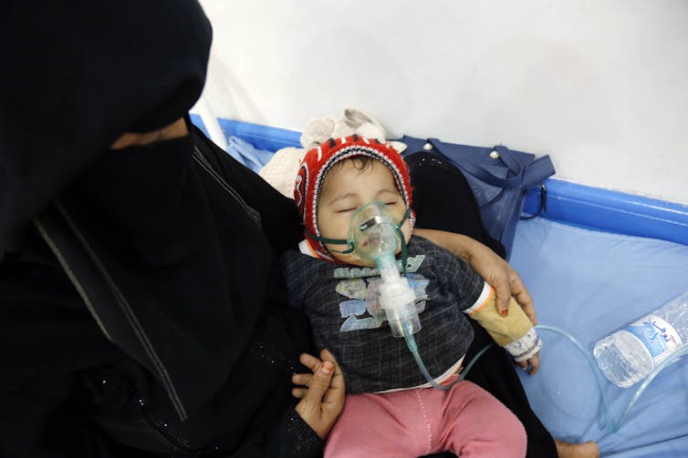 Mother holds her baby who receives medical treatment