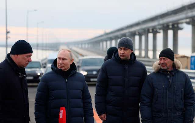 Russian president Putin with the Kerch bridge in the background after an attack damaged the bridge.