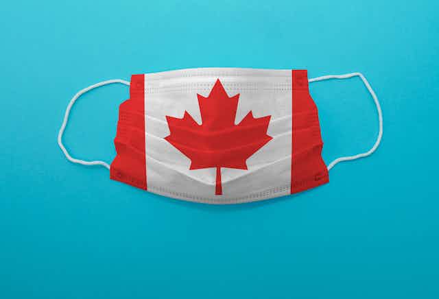 A surgical mask imprinted with the Canadian flag, against a blue background