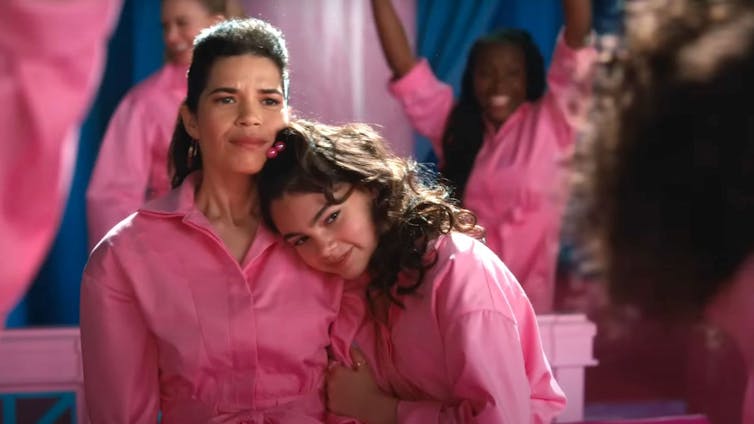 Mother wearing pink with teen girl resting head on mother's shoulder.