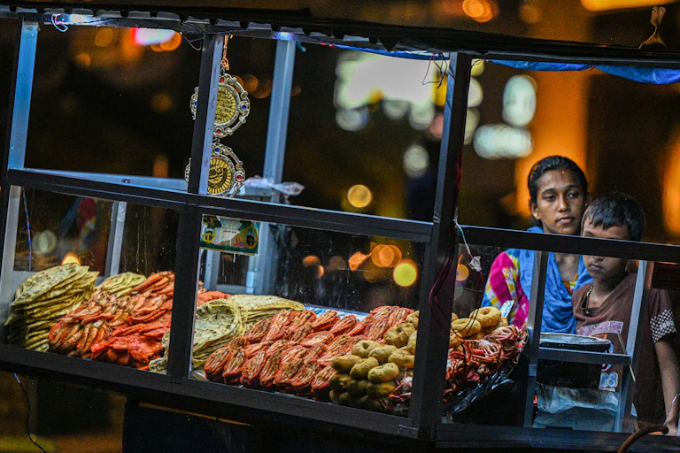 A woman and a boy stand next to a cart selling produce.