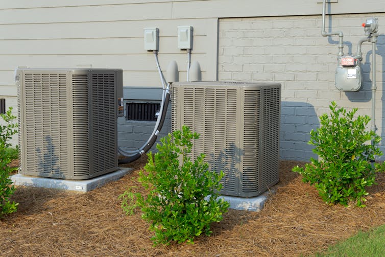 An electric heat pump installed next to a gas meter outside a home