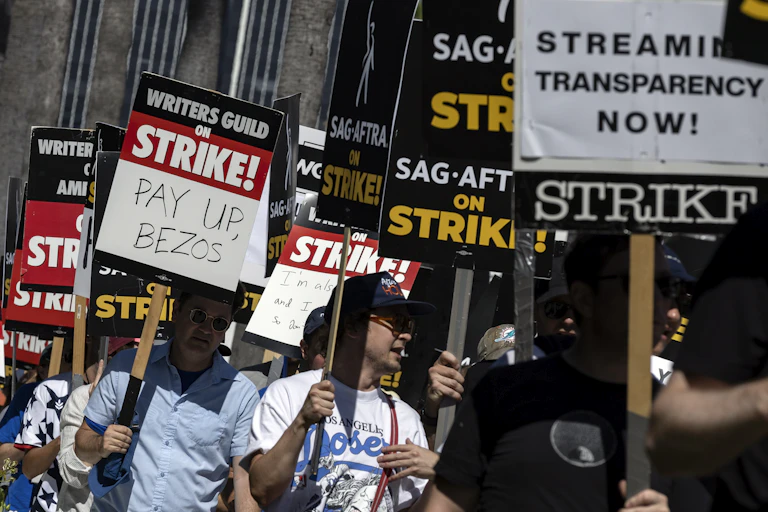 A demonstrator holds a poster reading 'Pay Up Bezos'