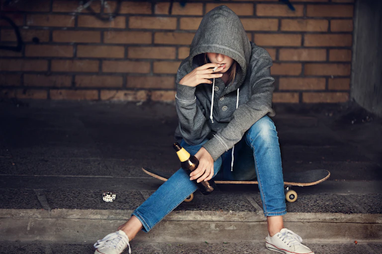Adolescente bebiendo alcohol y fumando