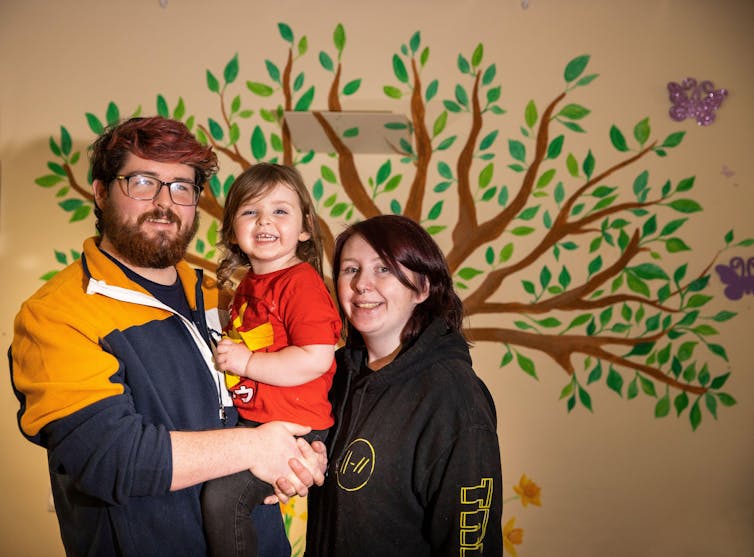 A family poses in front of a mural.