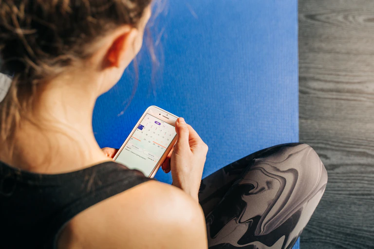 A woman looks at a calendar on her phone.