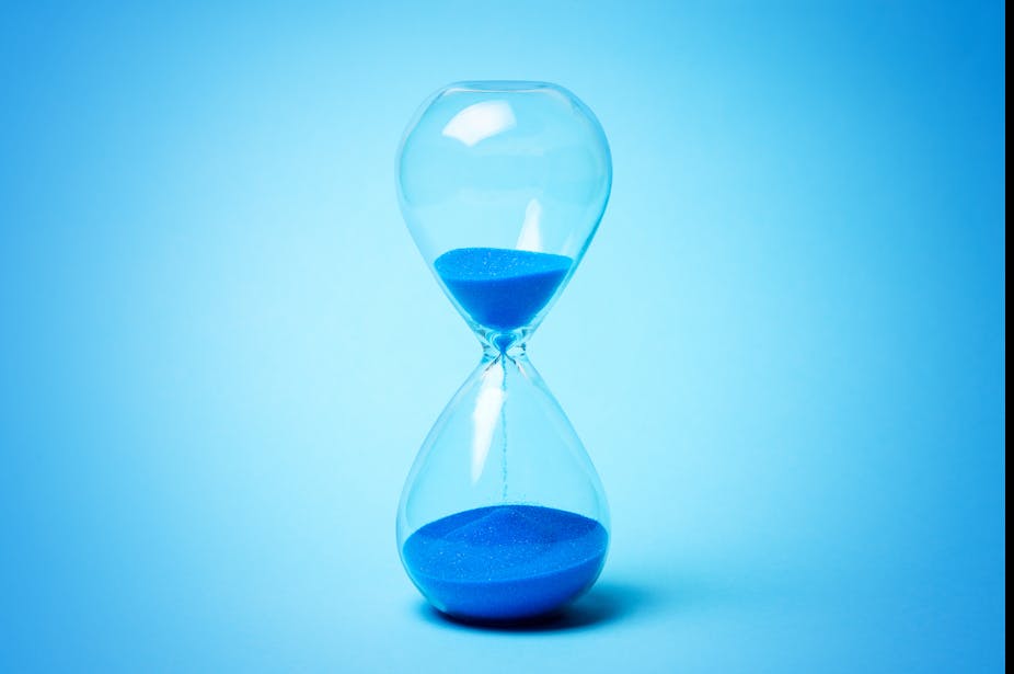 An hourglass with blue sand falling from top to bottom.