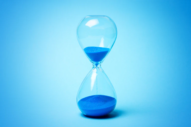 An hourglass with blue sand falling from top to bottom.