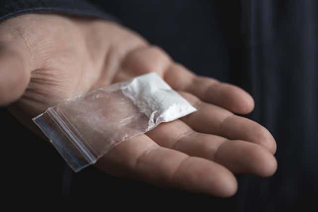 Hand holding a plastic bag containing drugs