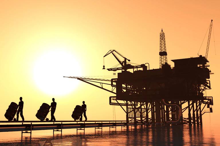 Oil workers pushing barrels out of an oil rig