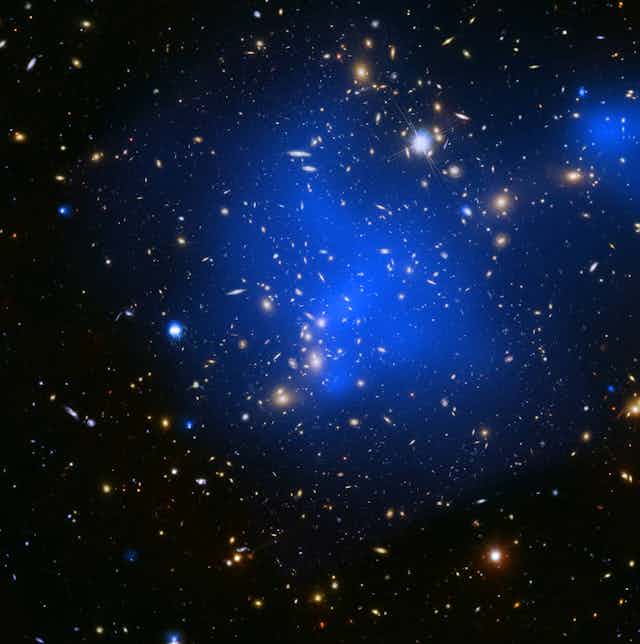 A cluster of many small, bright galaxies, surrounded by blue haze