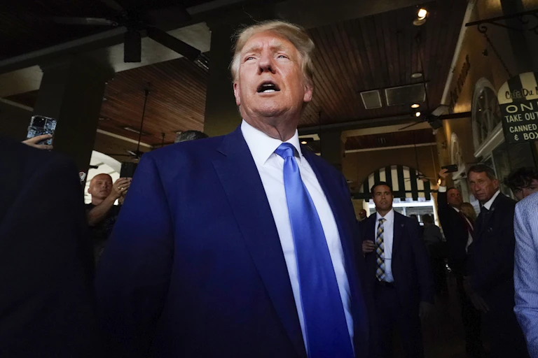 A man in a suit and tie stands in an open room.