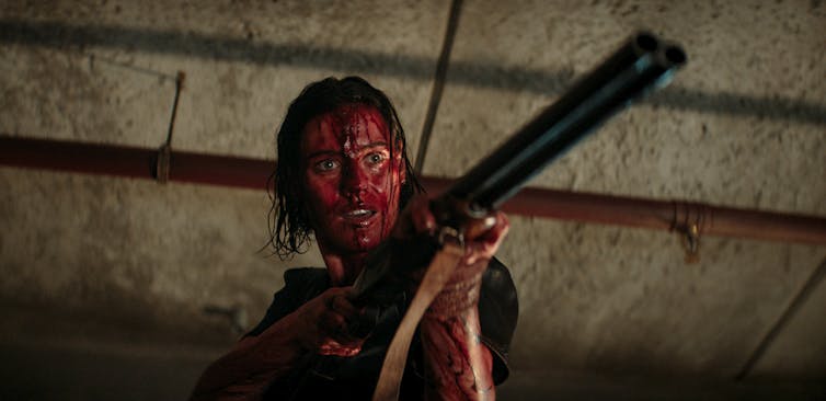 a woman seen covered with blood holding a weapon.