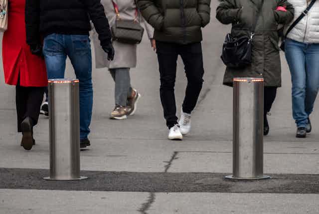 Two vertical posts at the entry to a street filled with pedestrians