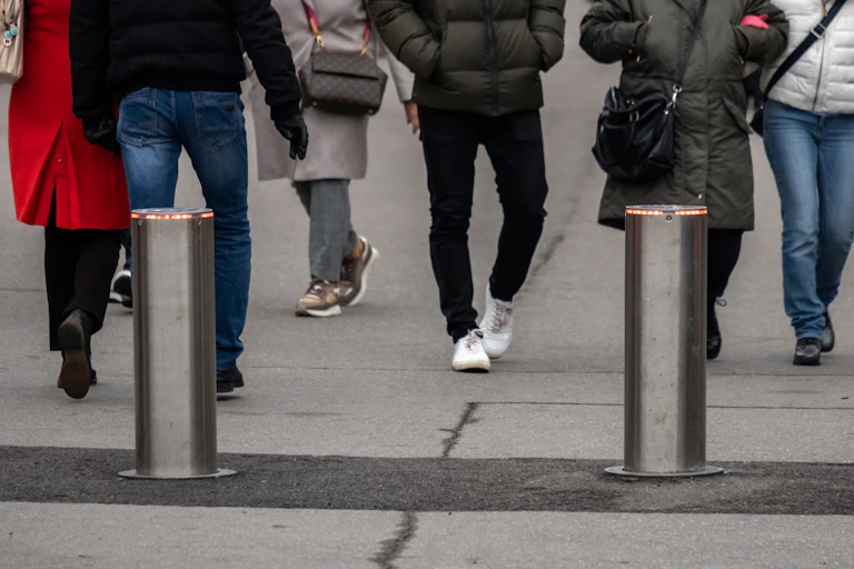 Two vertical posts at the entry to a street filled with pedestrians
