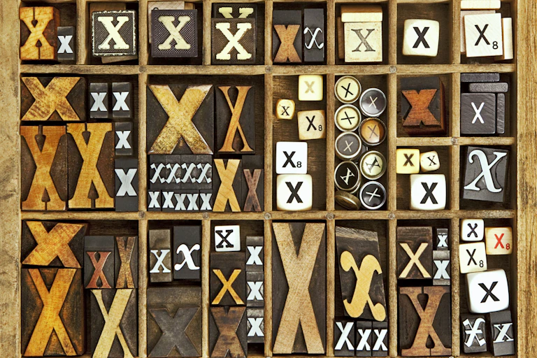 A bunch of letter x's arranged in a grid, on stamps, dice, buttons, or other carvings.