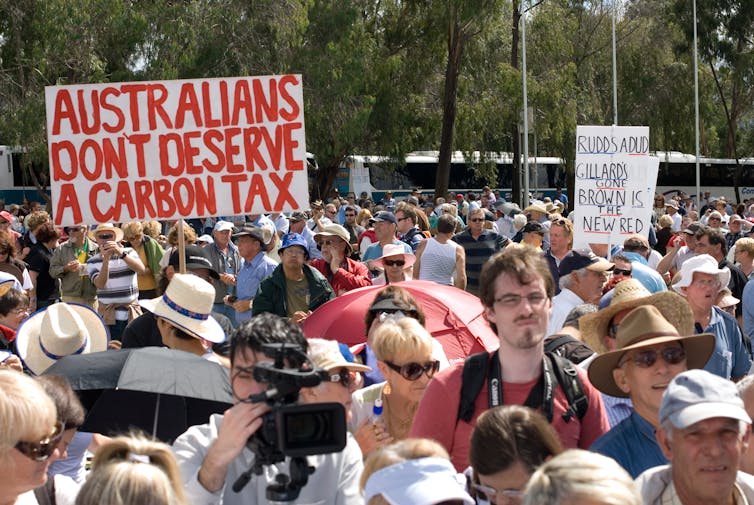 Protestors wave placards opposing a carbon tax
