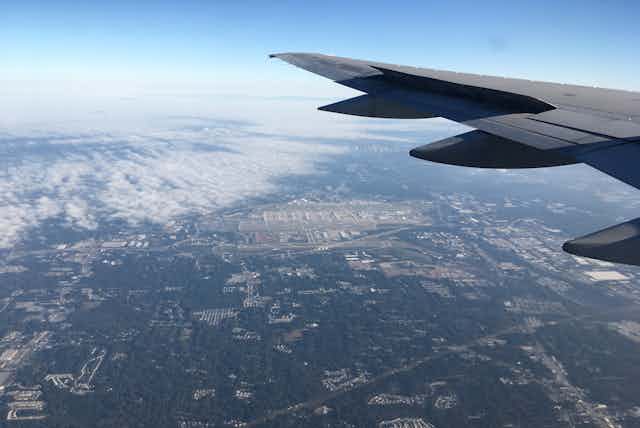 View from window of plane of wing and the Earth below.