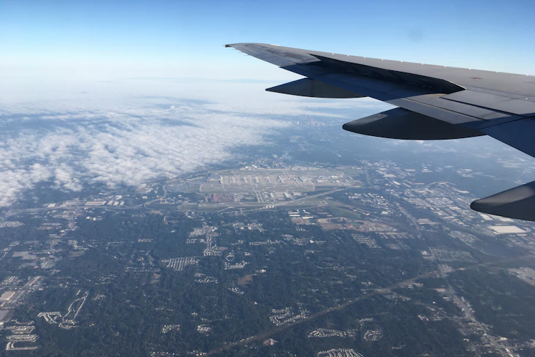 View from window of plane of wing and the Earth below.