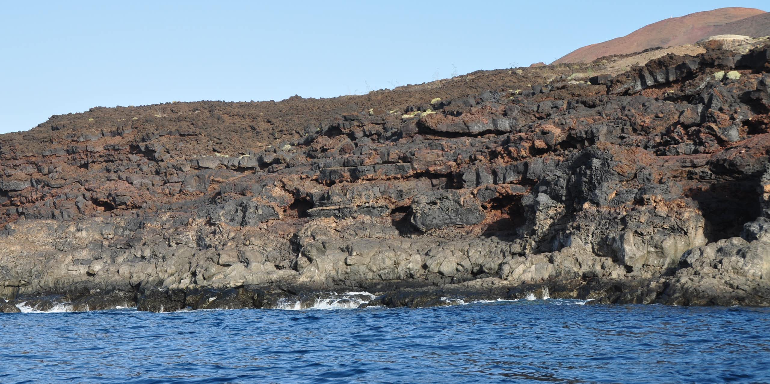 Acantilado de rocas oscuras en el mar.