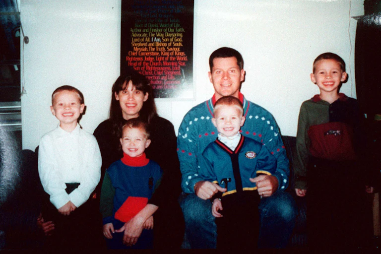 Family photo of husband, wife and four young children.
