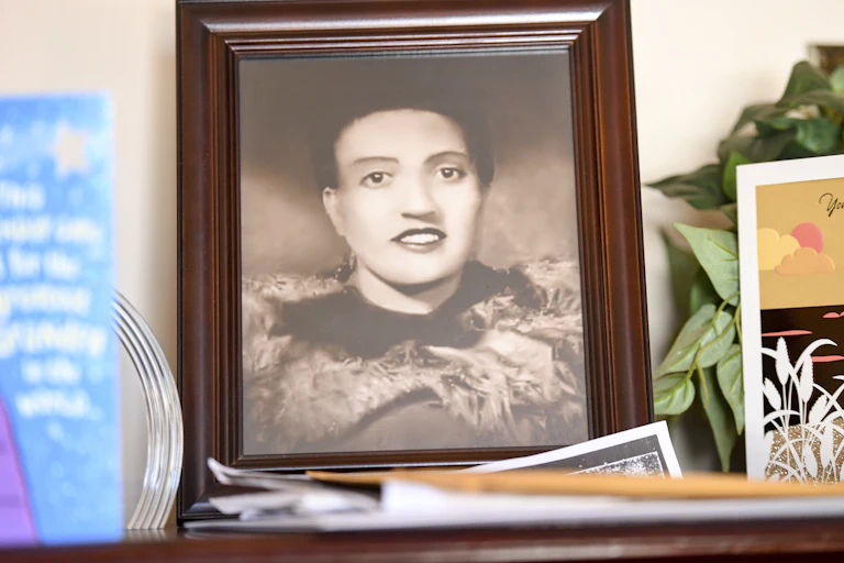 A framed, black and white photograph of woman rests atop a table.