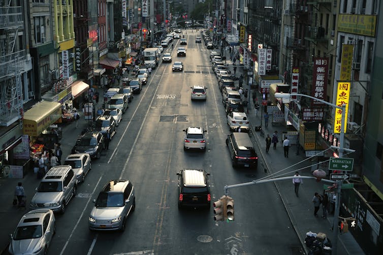 An overhead view shows a busy road between buildings.