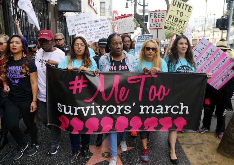 Women on a protest march hold a banner that says #MeToo Survivors' march.