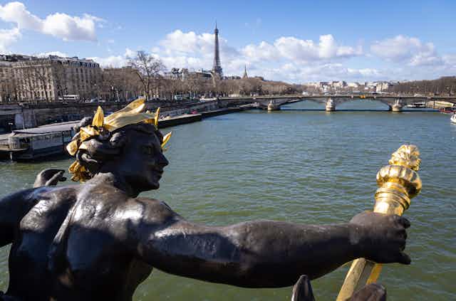 Statue looking out across the Seine River in Paris with Eiffel Tower in background