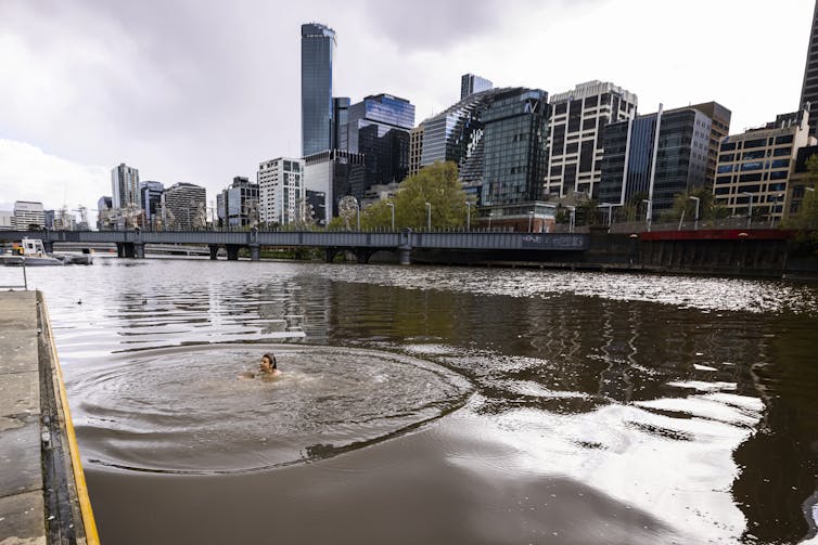 Woman swimming in river running through city