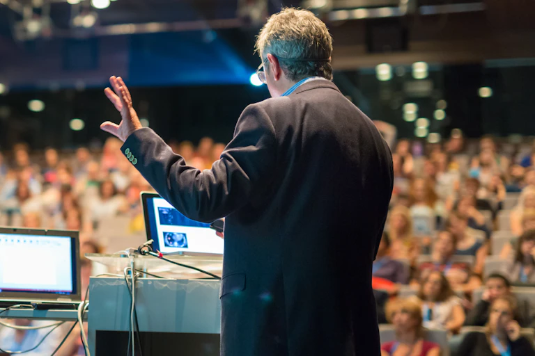 Lecturer talking to large lecture hall full of people