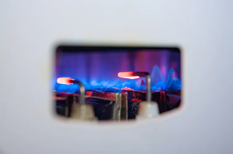 The blue pilot light in a white gas boiler.