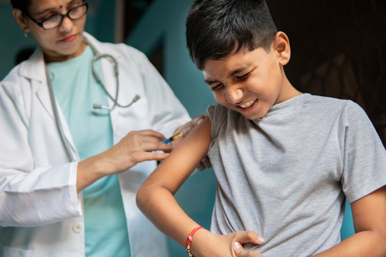 Female doctor giving injections to a young boy