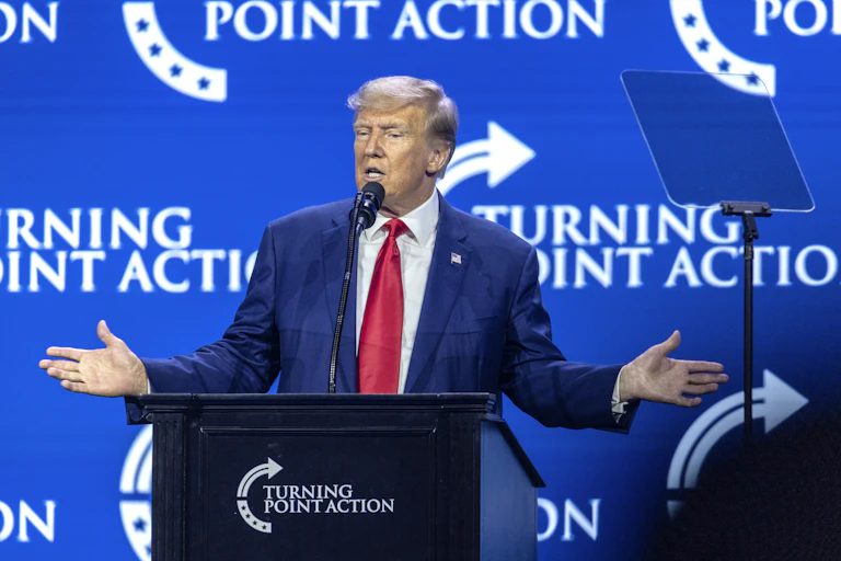 Donald Trump with his arms outstretched while making on a podium at the Turning POint Action rally, August 2023