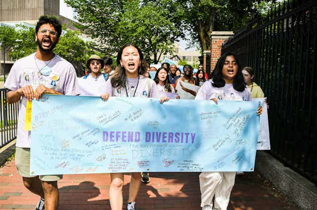 A group of protestors are marching and holding a sign that defends diversity.