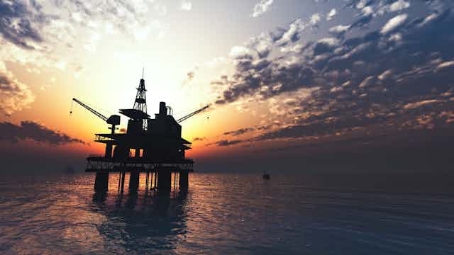 Oil rig at sea with sunset behind