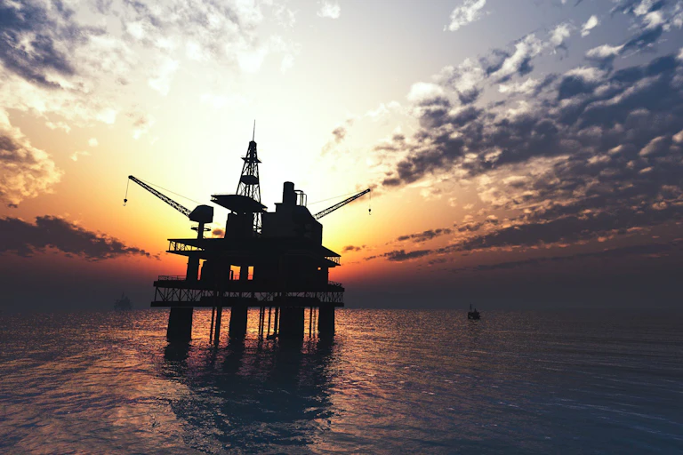 Oil rig at sea with sunset behind