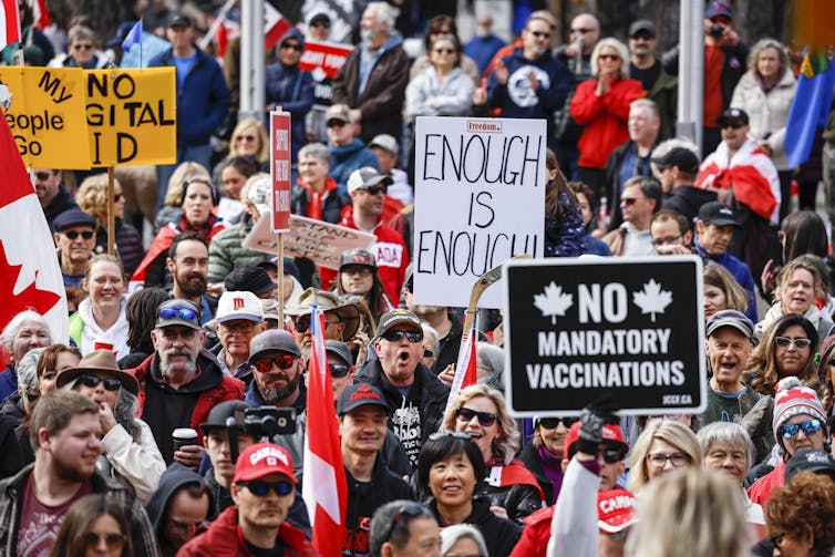 A crown of people with Canadian flags and signs reading'Enough is enough' and'NO mandatory vaccinations'