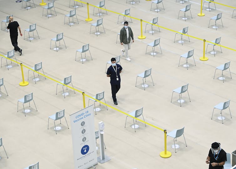 Four people seen from above in a large area of carefully spaced chairs