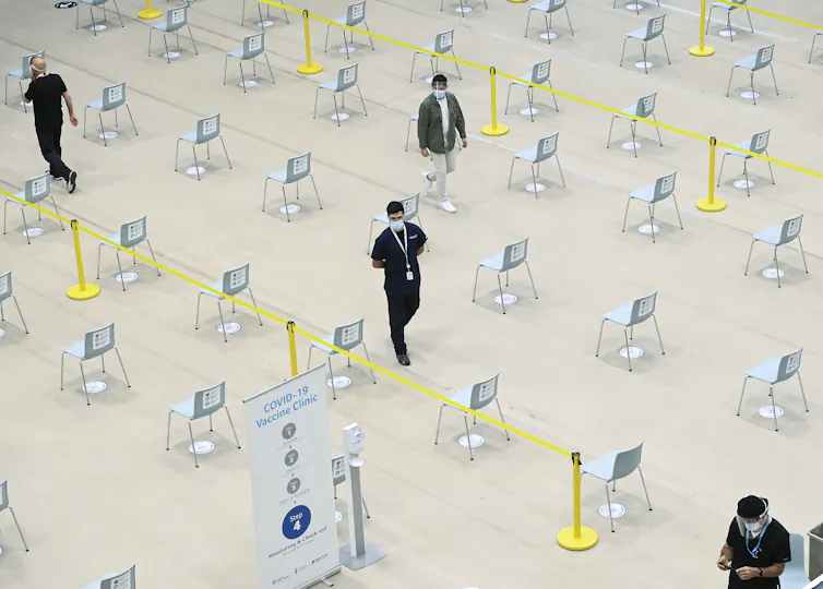 Four people seen from above in a large area of carefully spaced chairs
