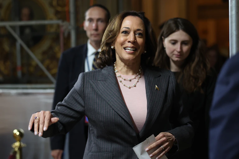 A woman wearing a blazer smiles as she walks.